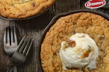 An image of two chocolate cookie skillets one covered in a scoop of Ice cream