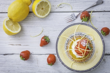 am image of a zesty lemon tart with lemons and strawberries