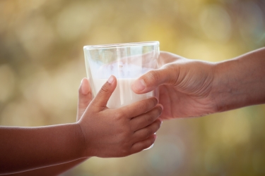 am image of a child and adult holding a glass of milk